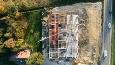 Modern bir binanın devam eden yapısını gösteren bir insansız hava aracı tarafından çekilen hava görüntüsü, yapıdaki çalışmaları, iskeleyi ve mekaniği vurguluyor.