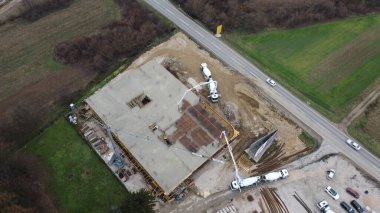 Modern bir binanın devam eden yapısını gösteren bir insansız hava aracı tarafından çekilen hava görüntüsü, yapıdaki çalışmaları, iskeleyi ve mekaniği vurguluyor.