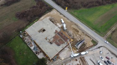 Modern bir binanın devam eden yapısını gösteren bir insansız hava aracı tarafından çekilen hava görüntüsü, yapıdaki çalışmaları, iskeleyi ve mekaniği vurguluyor.