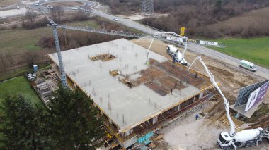 Modern bir binanın devam eden yapısını gösteren bir insansız hava aracı tarafından çekilen hava görüntüsü, yapıdaki çalışmaları, iskeleyi ve mekaniği vurguluyor.