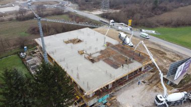 Modern bir binanın devam eden yapısını gösteren bir insansız hava aracı tarafından çekilen hava görüntüsü, yapıdaki çalışmaları, iskeleyi ve mekaniği vurguluyor.