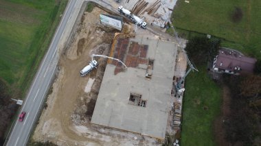 Modern bir binanın devam eden yapısını gösteren bir insansız hava aracı tarafından çekilen hava görüntüsü, yapıdaki çalışmaları, iskeleyi ve mekaniği vurguluyor.