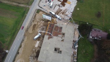 Modern bir binanın devam eden yapısını gösteren bir insansız hava aracı tarafından çekilen hava görüntüsü, yapıdaki çalışmaları, iskeleyi ve mekaniği vurguluyor.