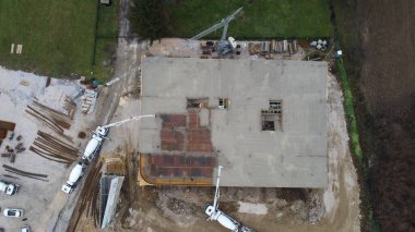 Modern bir binanın devam eden yapısını gösteren bir insansız hava aracı tarafından çekilen hava görüntüsü, yapıdaki çalışmaları, iskeleyi ve mekaniği vurguluyor.
