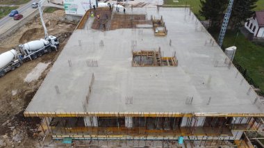 An aerial view captured by a drone showcasing the ongoing construction of a modern building, highlighting the work on the structure, scaffolding, and machinery on site clipart