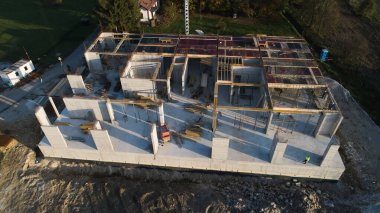 Modern bir binanın devam eden yapısını gösteren bir insansız hava aracı tarafından çekilen hava görüntüsü, yapıdaki çalışmaları, iskeleyi ve mekaniği vurguluyor.