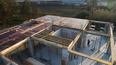 Modern bir binanın devam eden yapısını gösteren bir insansız hava aracı tarafından çekilen hava görüntüsü, yapıdaki çalışmaları, iskeleyi ve mekaniği vurguluyor.