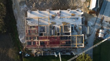 Modern bir binanın devam eden yapısını gösteren bir insansız hava aracı tarafından çekilen hava görüntüsü, yapıdaki çalışmaları, iskeleyi ve mekaniği vurguluyor.