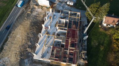 Modern bir binanın devam eden yapısını gösteren bir insansız hava aracı tarafından çekilen hava görüntüsü, yapıdaki çalışmaları, iskeleyi ve mekaniği vurguluyor.