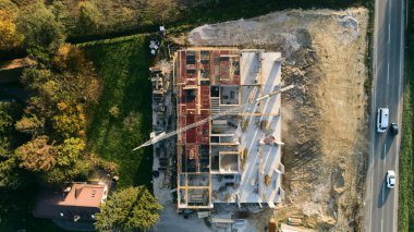 Modern bir binanın devam eden yapısını gösteren bir insansız hava aracı tarafından çekilen hava görüntüsü, yapıdaki çalışmaları, iskeleyi ve mekaniği vurguluyor.