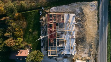 Modern bir binanın devam eden yapısını gösteren bir insansız hava aracı tarafından çekilen hava görüntüsü, yapıdaki çalışmaları, iskeleyi ve mekaniği vurguluyor.