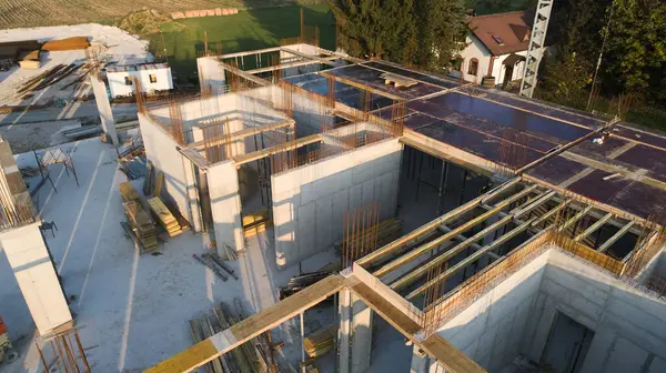 Modern bir binanın devam eden yapısını gösteren bir insansız hava aracı tarafından çekilen hava görüntüsü, yapıdaki çalışmaları, iskeleyi ve mekaniği vurguluyor.