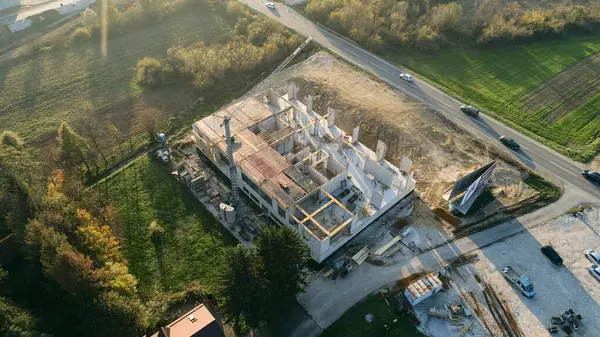 Modern bir binanın devam eden yapısını gösteren bir insansız hava aracı tarafından çekilen hava görüntüsü, yapıdaki çalışmaları, iskeleyi ve mekaniği vurguluyor.