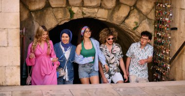 Yaz kıyafetleri içinde çeşitli turist grupları, geniş tebessümleriyle turistik şehirde geziniyor, gezintilerinin tadını çıkarıyorlar.. 