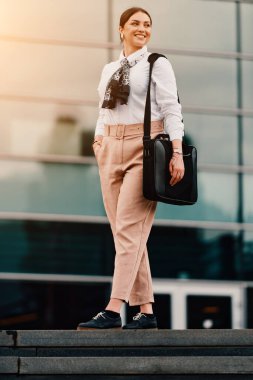 A stylish Latina businesswoman confidently walks the bustling city streets, her briefcase in hand and a determined smile on her face.  clipart