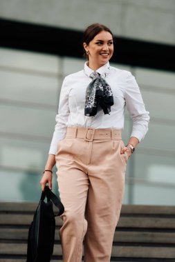 Şık bir Latin iş kadını şehrin hareketli sokaklarında elinde evrak çantası ve yüzünde kararlı bir gülümseme ile rahatça yürüyor.. 