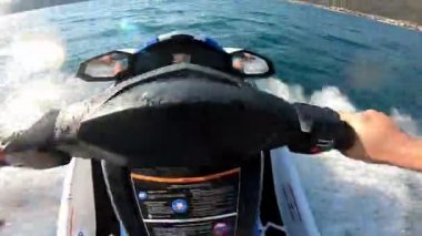 Açık denizde yüksek hızda jet ski süren bir adamın ilk görüntüsü. POV aksiyon görüntüleri, aşırı bir yaz su sporu aktivitesi sırasında dinamik hareketler, su sıçramaları ve güçlü dönüşler gösteriyor..
