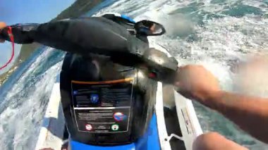 Açık denizde yüksek hızda jet ski süren bir adamın ilk görüntüsü. POV aksiyon görüntüleri, aşırı bir yaz su sporu aktivitesi sırasında dinamik hareketler, su sıçramaları ve güçlü dönüşler gösteriyor..