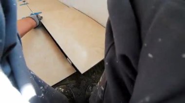 Seramik döşeme döşemesi takan profesyonel bir klasörün POV görüntüsü. Video, fayans yapıştırıcı sürme, fayansları yerleştirme ve onları zemine sabitlemek için bir çekiç kullanma sürecini kaydediyor. İdeal