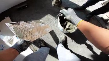 Seramik döşeme döşemesi takan profesyonel bir klasörün POV görüntüsü. Video, fayans yapıştırıcı sürme, fayansları yerleştirme ve onları zemine sabitlemek için bir çekiç kullanma sürecini kaydediyor. İdeal