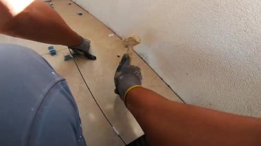 Seramik döşeme döşemesi takan profesyonel bir klasörün POV görüntüsü. Video, fayans yapıştırıcı sürme, fayansları yerleştirme ve onları zemine sabitlemek için bir çekiç kullanma sürecini kaydediyor. İdeal