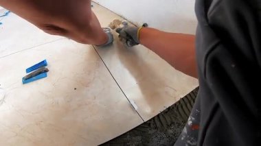 Seramik döşeme döşemesi takan profesyonel bir klasörün POV görüntüsü. Video, fayans yapıştırıcı sürme, fayansları yerleştirme ve onları zemine sabitlemek için bir çekiç kullanma sürecini kaydediyor. İdeal