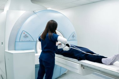 Hemşire ya da tıbbi teknisyen hastayı MRI taraması ya da MRI tarayıcısı için hazırlar..