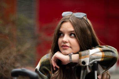 Açık havada günlük kıyafetlerle gülümseyen neşeli genç bir kadının yakın portresi. Açık havada gülümseyen kızın portresini kapat.