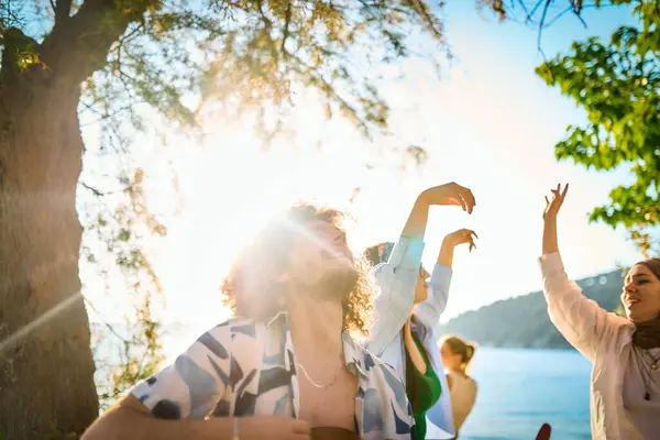 Bir grup arkadaş plajda toplanıp müzik, kahkaha ve birlikteliğin sıcaklığıyla dolu neşeli anları paylaşıyorlar. Gençler sahilde eğleniyor.