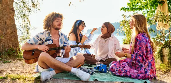 Bir grup arkadaş plajda toplanıp müzik, kahkaha ve birlikteliğin sıcaklığıyla dolu neşeli anları paylaşıyorlar. Gençler sahilde eğleniyor.