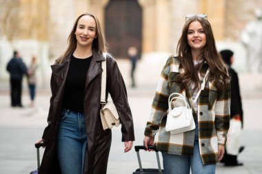 İki Genç Kadın Bavulla Seyahat Ediyor. İki şık genç bayan ellerinde bavullarla geziyorlar, seyahat sırasında bir şehir merkezini keşfediyorlar..