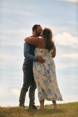 Çimenli bir dağ tarlasında neşeli bir şekilde dans eden erkek ve kadın aydınlık bir günde, doğada sevgi ve özgürlüğün tadını çıkarıyorlar..