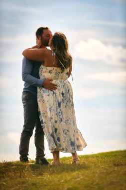 Çimenli bir dağ tarlasında neşeli bir şekilde dans eden erkek ve kadın aydınlık bir günde, doğada sevgi ve özgürlüğün tadını çıkarıyorlar..