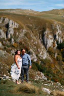 Sonbahar boyunca manzaralı bir dağ manzarasında kucaklaşan romantik çift, açık havanın ve aşkın tadını çıkarıyor..