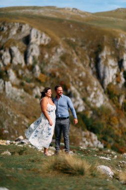 Sonbahar boyunca manzaralı bir dağ manzarasında kucaklaşan romantik çift, açık havanın ve aşkın tadını çıkarıyor..