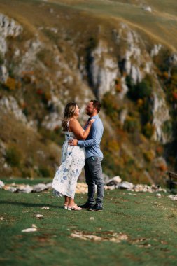 Sonbahar boyunca manzaralı bir dağ manzarasında kucaklaşan romantik çift, açık havanın ve aşkın tadını çıkarıyor..