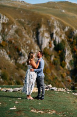 Sonbahar boyunca manzaralı bir dağ manzarasında kucaklaşan romantik çift, açık havanın ve aşkın tadını çıkarıyor..