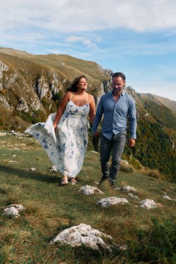 Sonbahar boyunca manzaralı bir dağ yolunda el ele yürüyen çift, doğanın tadını çıkarıyor ve birbirlerine eşlik ediyorlar..