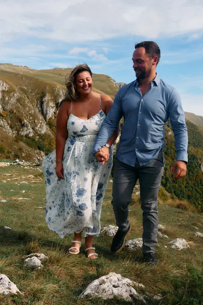 Sonbahar boyunca manzaralı bir dağ yolunda el ele yürüyen çift, doğanın tadını çıkarıyor ve birbirlerine eşlik ediyorlar..