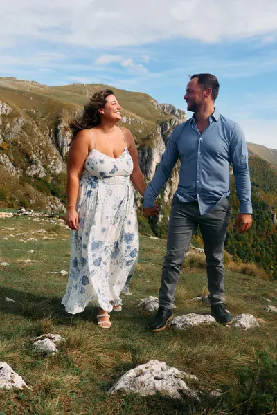 Sonbahar boyunca manzaralı bir dağ yolunda el ele yürüyen çift, doğanın tadını çıkarıyor ve birbirlerine eşlik ediyorlar..