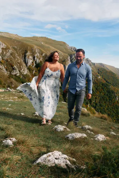 Sonbahar boyunca manzaralı bir dağ yolunda el ele yürüyen çift, doğanın tadını çıkarıyor ve birbirlerine eşlik ediyorlar..