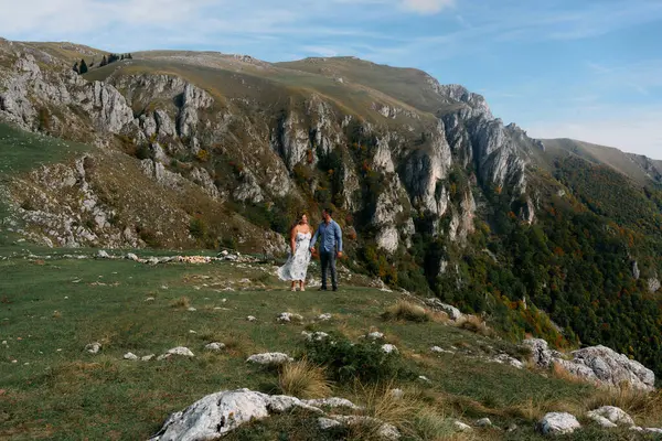 Sonbahar boyunca manzaralı bir dağ yolunda el ele yürüyen çift, doğanın tadını çıkarıyor ve birbirlerine eşlik ediyorlar..