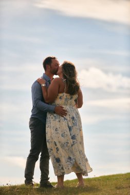 Çimenli bir dağ tarlasında neşeli bir şekilde dans eden erkek ve kadın aydınlık bir günde, doğada sevgi ve özgürlüğün tadını çıkarıyorlar..