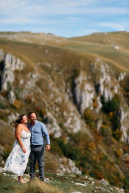 Sonbahar boyunca manzaralı bir dağ manzarasında kucaklaşan romantik çift, açık havanın ve aşkın tadını çıkarıyor..