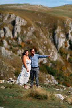 Sonbahar boyunca manzaralı bir dağ manzarasında kucaklaşan romantik çift, açık havanın ve aşkın tadını çıkarıyor..