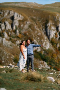 Sonbahar boyunca manzaralı bir dağ manzarasında kucaklaşan romantik çift, açık havanın ve aşkın tadını çıkarıyor..