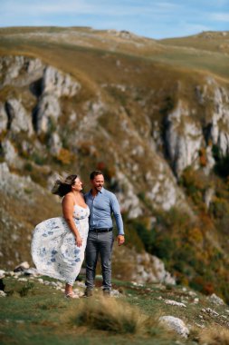 Sonbahar boyunca manzaralı bir dağ manzarasında kucaklaşan romantik çift, açık havanın ve aşkın tadını çıkarıyor..