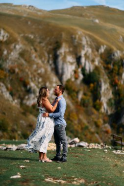 Sonbahar boyunca manzaralı bir dağ manzarasında kucaklaşan romantik çift, açık havanın ve aşkın tadını çıkarıyor..
