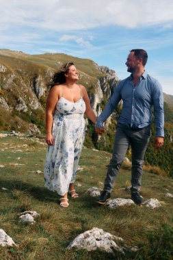 Sonbahar boyunca manzaralı bir dağ yolunda el ele yürüyen çift, doğanın tadını çıkarıyor ve birbirlerine eşlik ediyorlar..