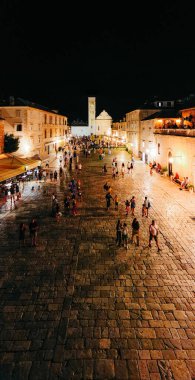 Kalabalık tarihi Hvar şehir meydanının gece fotoğrafı. Kilise ve taş binalar, popüler turistik gece hayatı merkezleri..